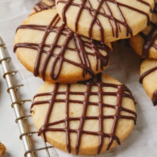 Close up on chocolate drizzled shortbread cookies against white background