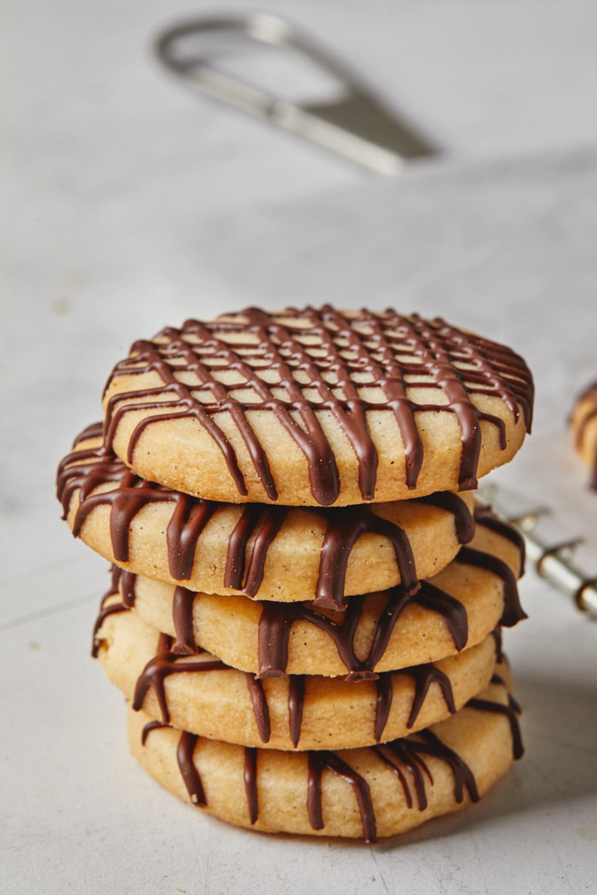 A stack of the best shortbread cookies drizzled with chocolate on a white countertop.