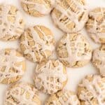 A closeup of iced butter cookies on a plate with icing drizzled over the top.