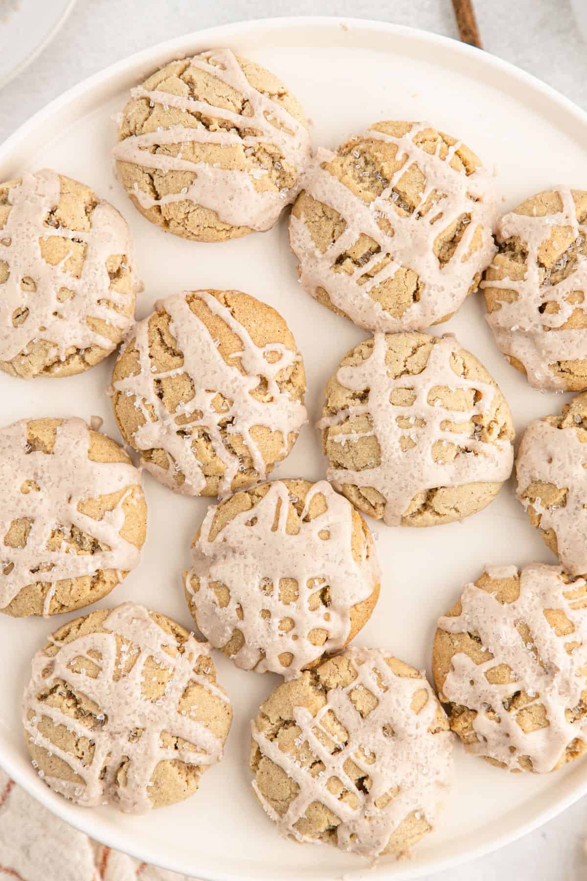 A closeup of iced eggnog cookies on a plate with icing drizzled over the top.