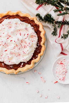 Peppermint Chocolate Pie with crushed peppermint against white background with Christmas tree and red and white napkin