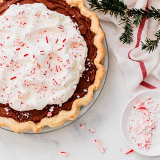 Peppermint Chocolate Pie with crushed peppermint against white background with Christmas tree and red and white napkin