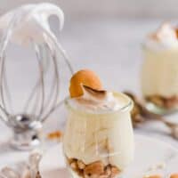 Straight on shot of homemade banana pudding in mini glasses with nilla cookies and meringue