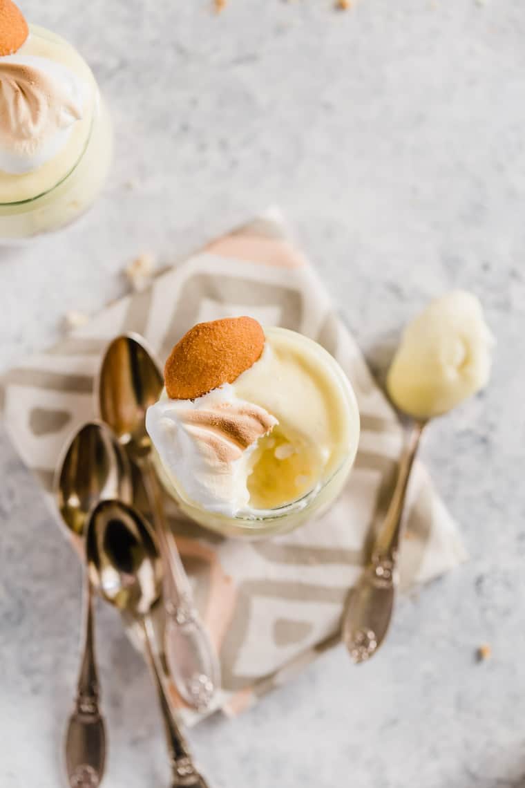 Overhead shot of one homemade banana pudding recipe in a mini glass with nilla cookie and meringue with a spoon of some out