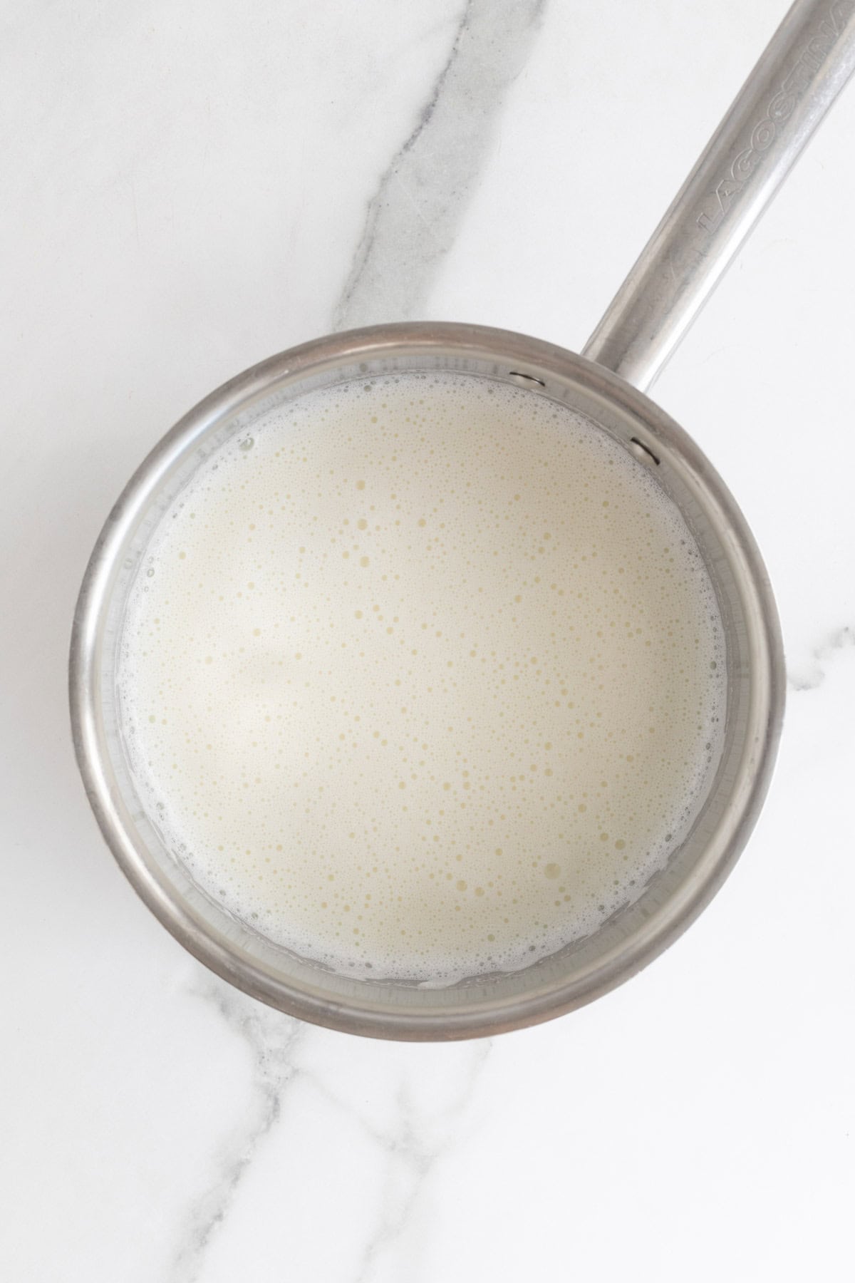 Simmering milk steaming in a pot on white countertop