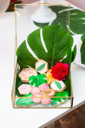 Birthday cookies in the shape of Hawaiian plants and flowers in a glass box display