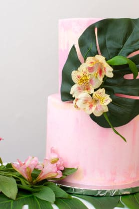 Harmony's first birthday cake with a pink colored frosting and topped with fresh Hawaiian flowers