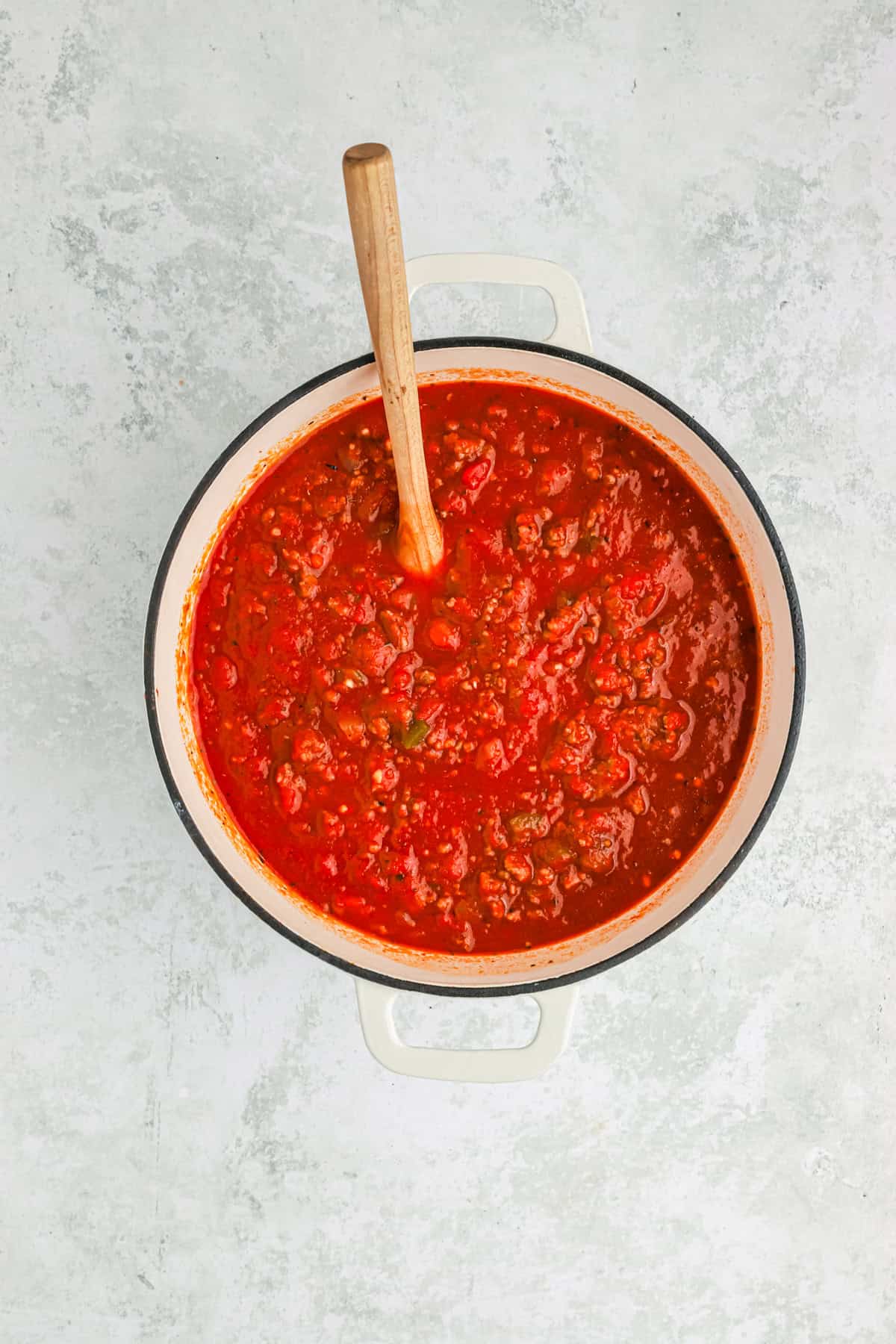 Finished homemade spaghetti sauce in a large pot with a wooden spoon