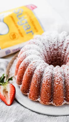 Fresh Strawberry Bundt Cake with Powdered Sugar on top and a bag of sugar in the background