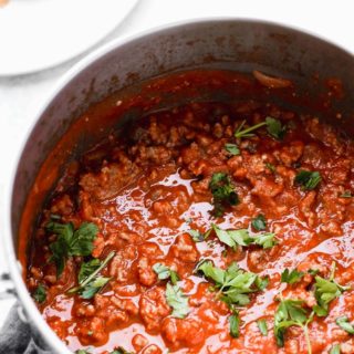 Big pot of homemade spaghetti sauce against white background