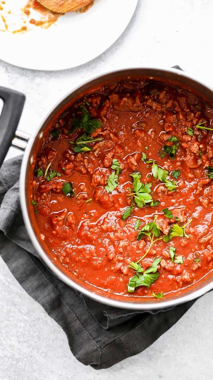 Photo overhead of big pot of homemade spaghetti sauce recipe against white background