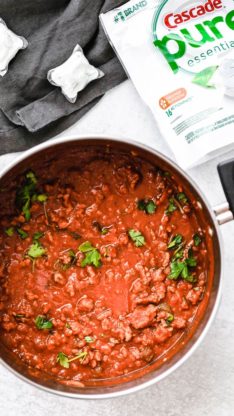 Big pot of Easy Homemade spaghetti sauce recipe against white background with Cascade pure Essentials above the pot.