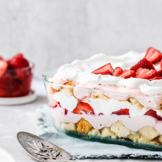 Side view of Strawberry Punch Bowl Cake against white background with bowl of strawberries