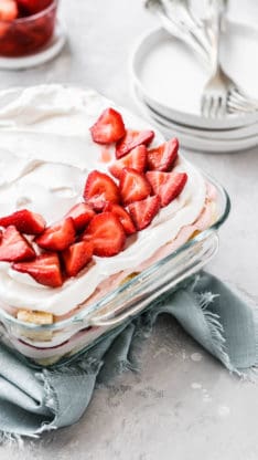 Side overview of Strawberry Punch Bowl Cake with white plates and forks in the background for serving