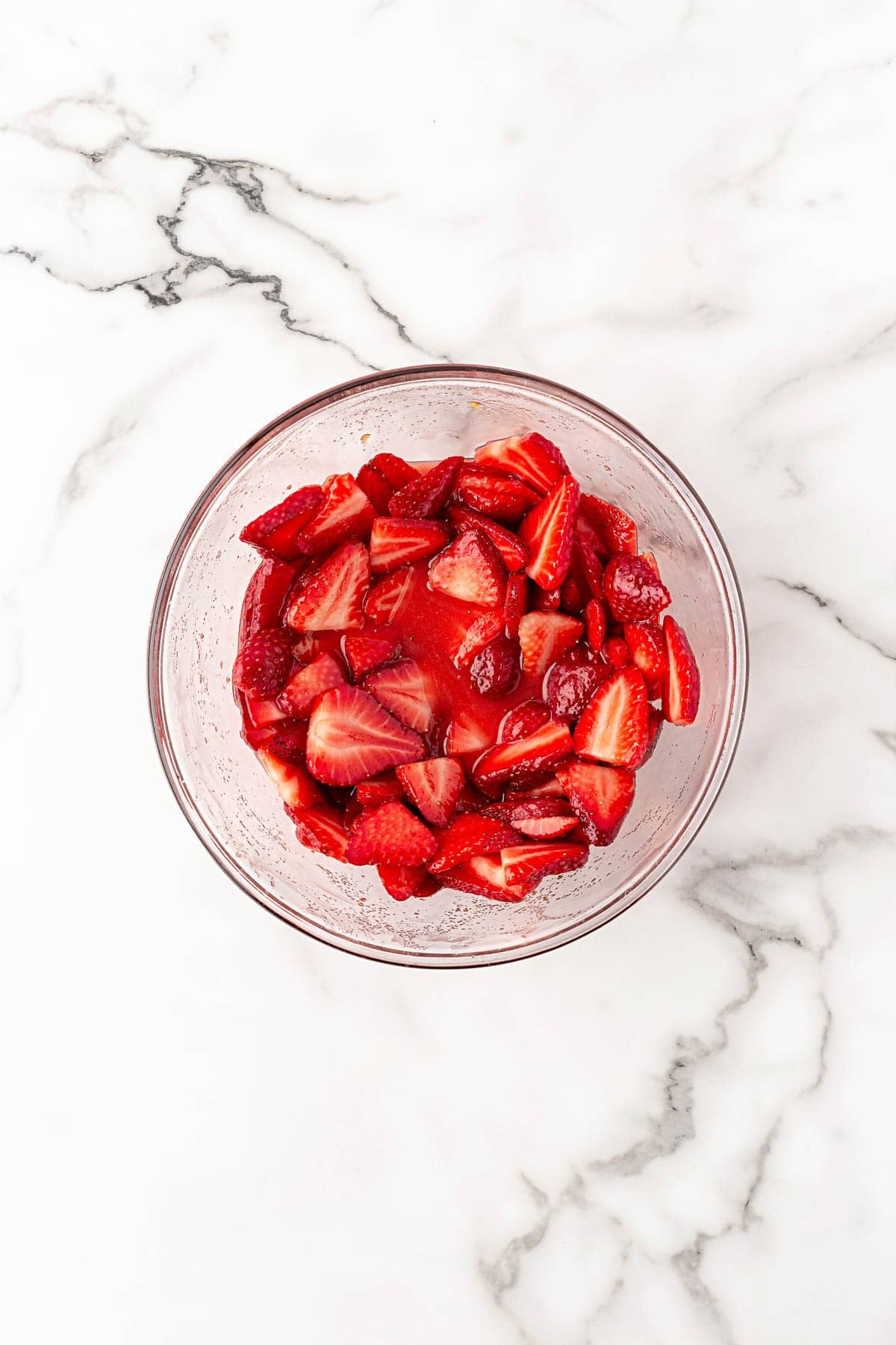 Bowl of sliced strawberries mixed with sugar and juices