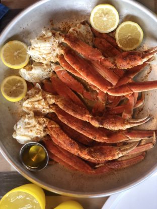 Overhead shot of several crab legs served with butter and lemons at the Carnival Horizon Seafood Shack
