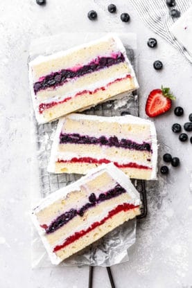 Overhead shot of slices of Berry Icebox Cake with fresh blueberries and a sliced strawberry next to them