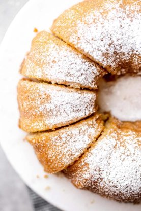 Overhead of sliced Kentucky Butter Cake recipe with powdered sugar topping against white cake stand