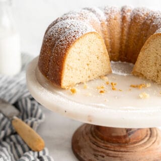 Sliced Kentucky Butter Cake recipe on white cake stand with a slice of cake on white plate