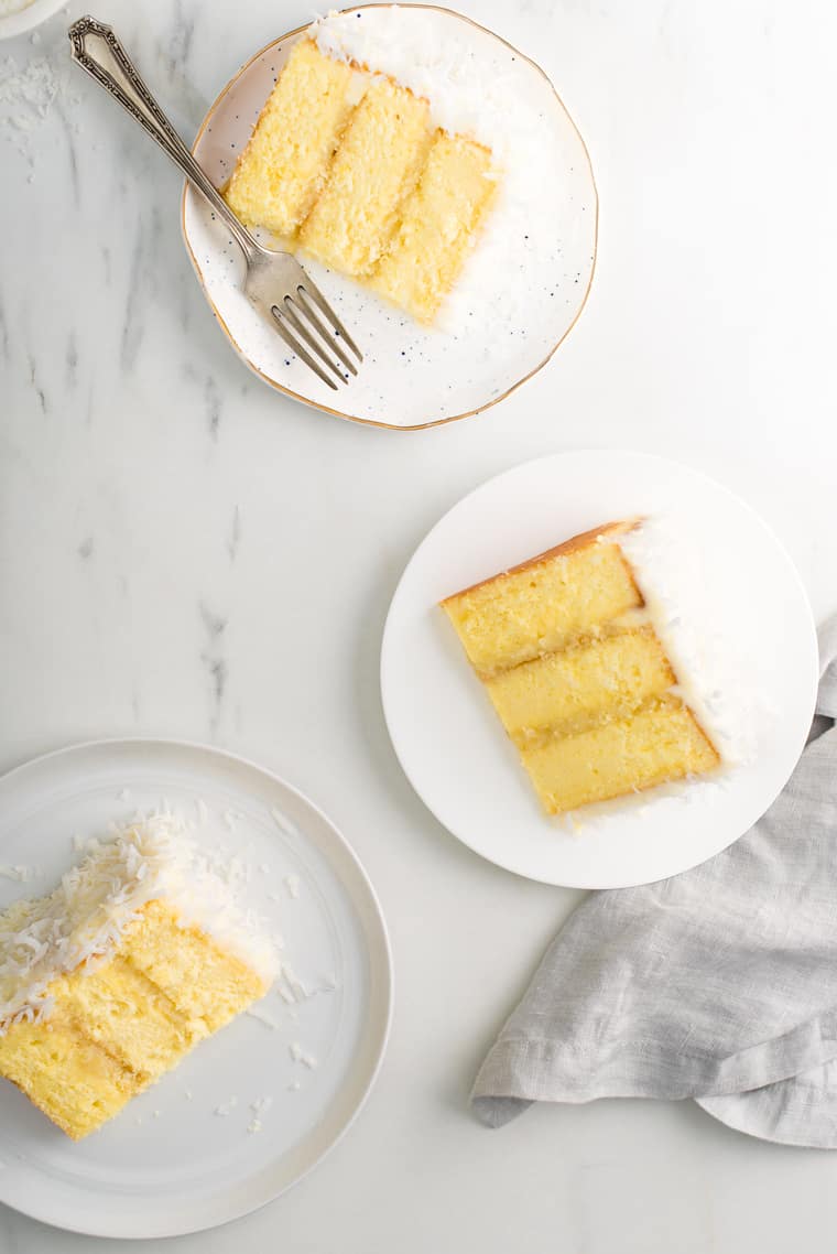 Overhead of three slices of Pineapple Coconut Cake on white plates