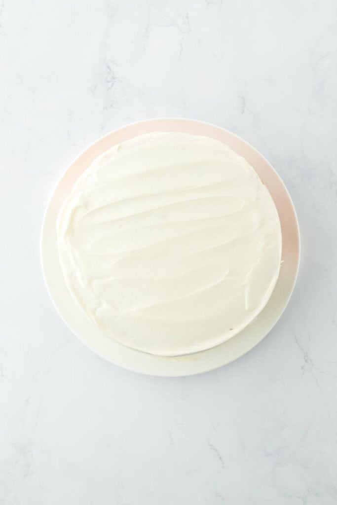 Cake fully frosted with cream cheese frosting on a plate