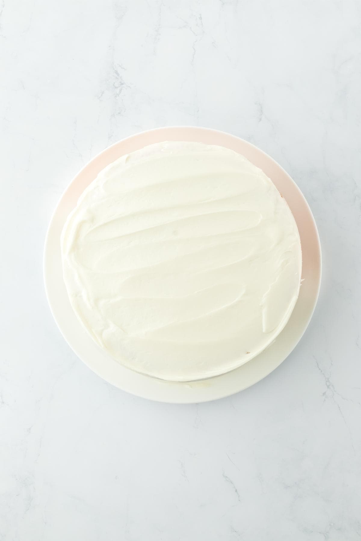 Cake fully frosted with cream cheese frosting on a plate