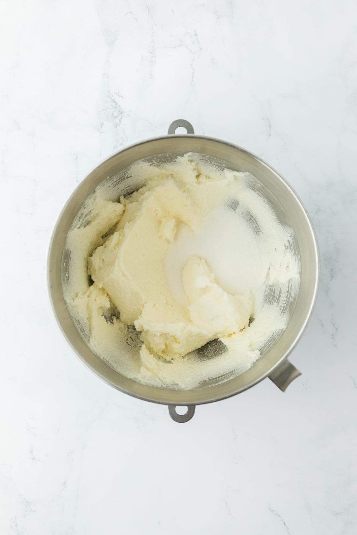 Creamed butter and sugar mixture in a stainless steel mixing bowl