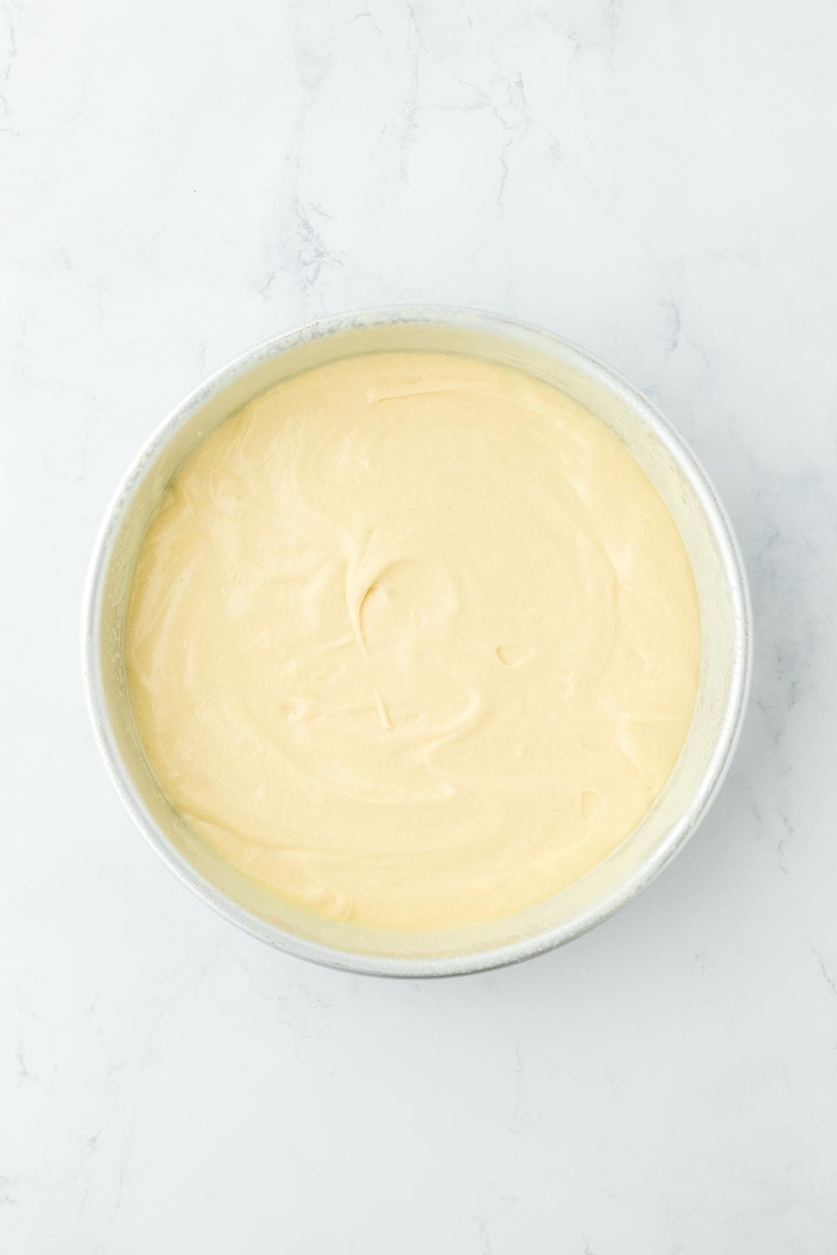 Cake batter evenly spread in a round cake pan, ready for baking