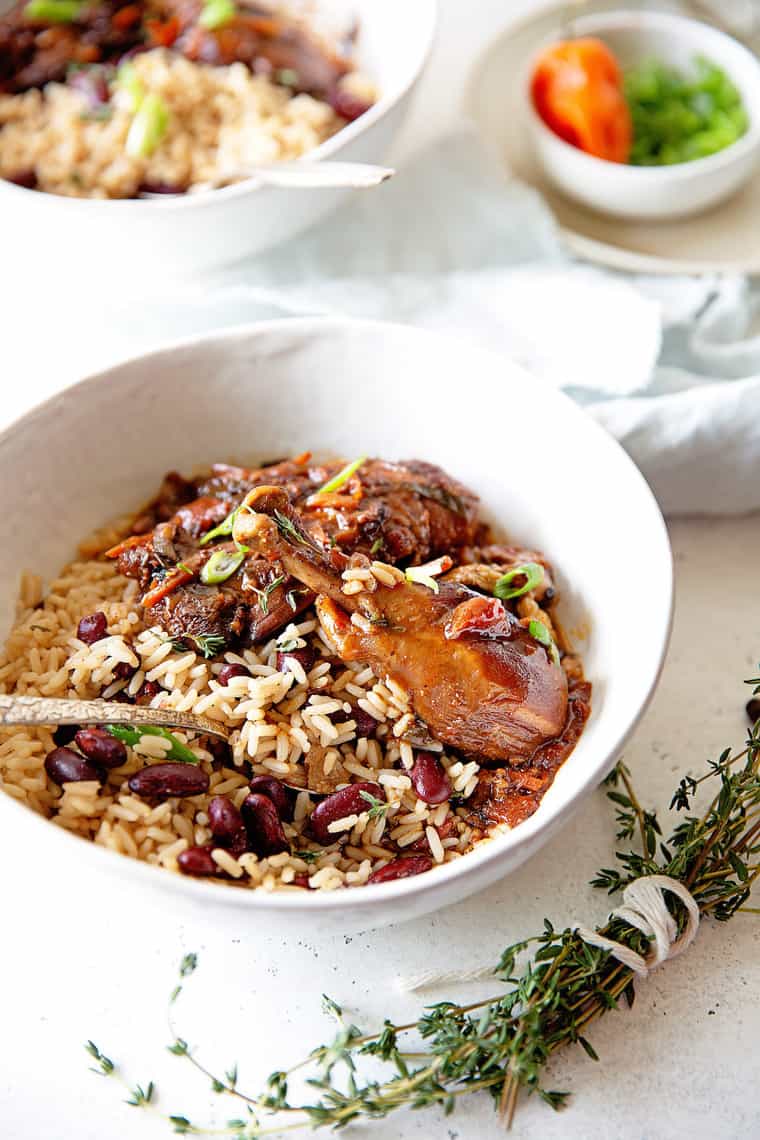 Brown Stew Chicken over Rice and Peas in white bowl