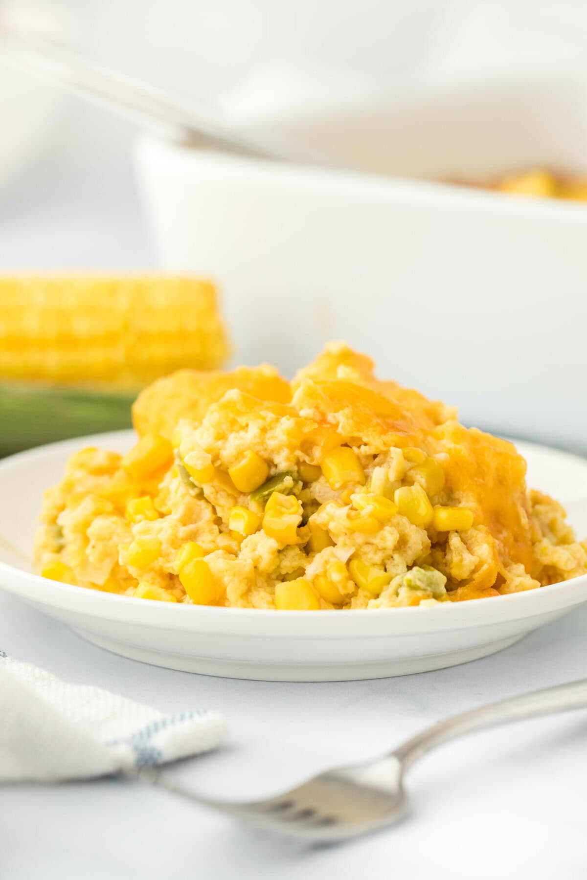 A large serving of the best corn pudding on a white plate in a white background