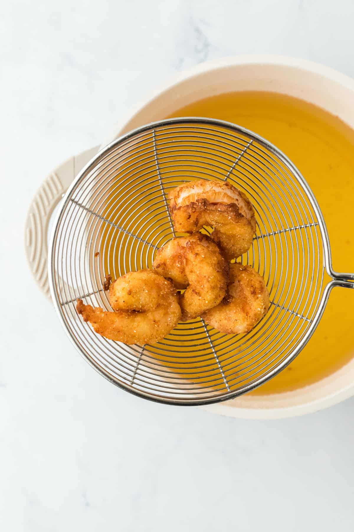 Fried shrimp for a poboy recipe coming out of hot oil after being fried