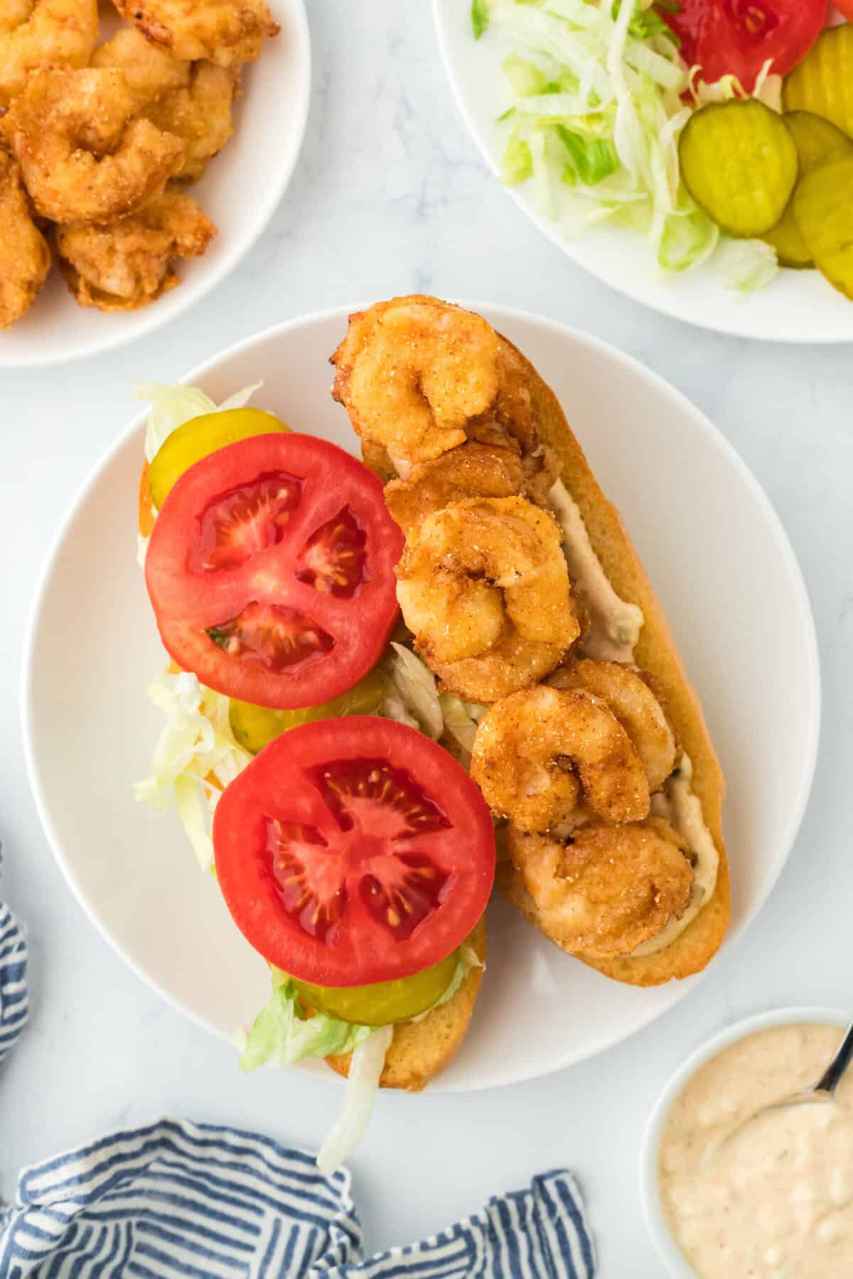 Dressed shrimp po boy recipe on a white plate openfaced