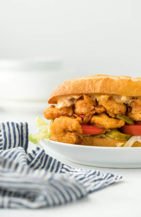 A fried shrimp po boy close up on a white plate ready to enjoy in white background