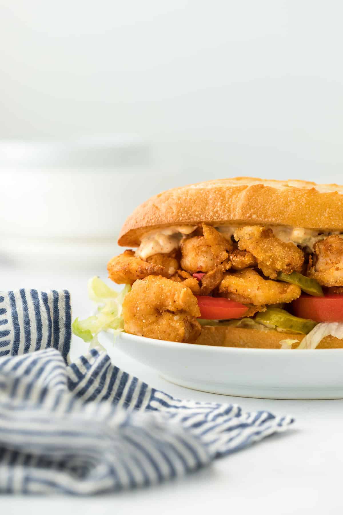 A fried shrimp po boy close up on a white plate ready to enjoy in white background