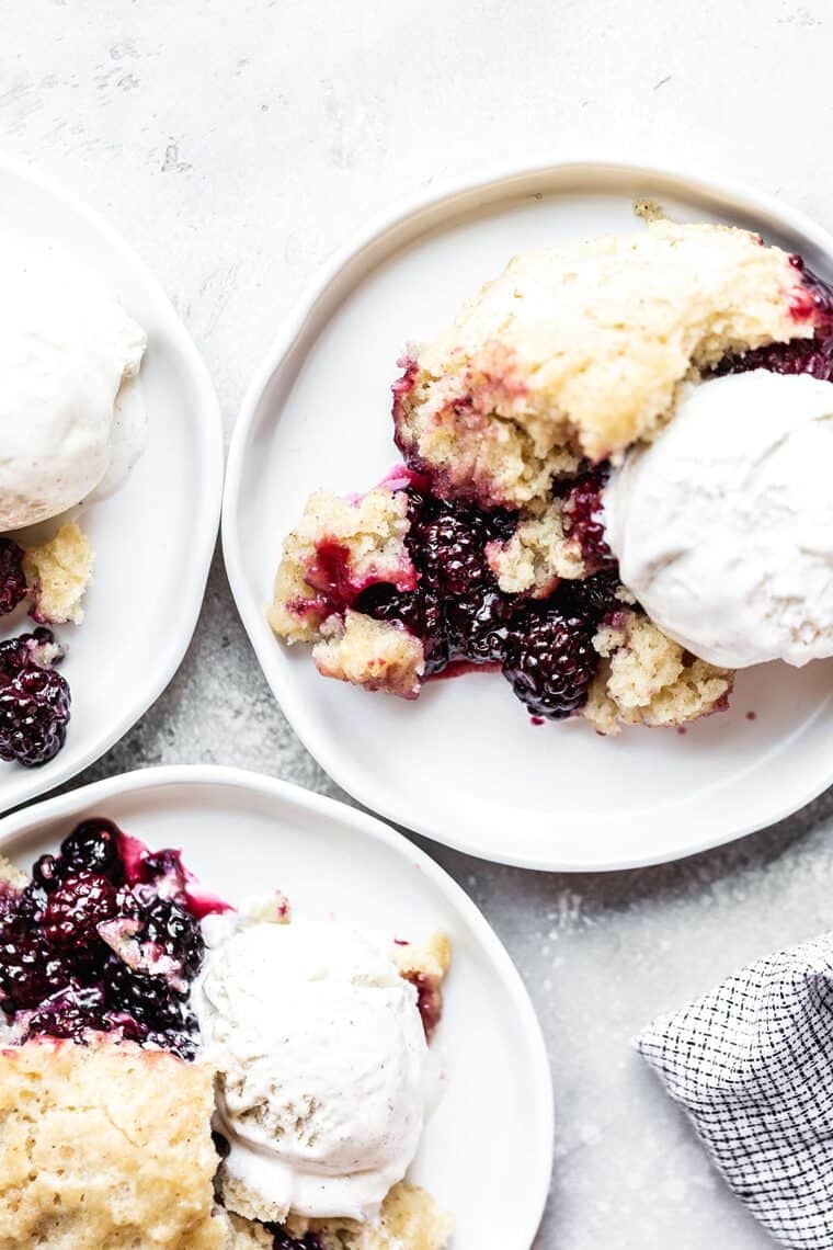 Overhead of southern blackberry cobbler on white plates with vanilla ice cream