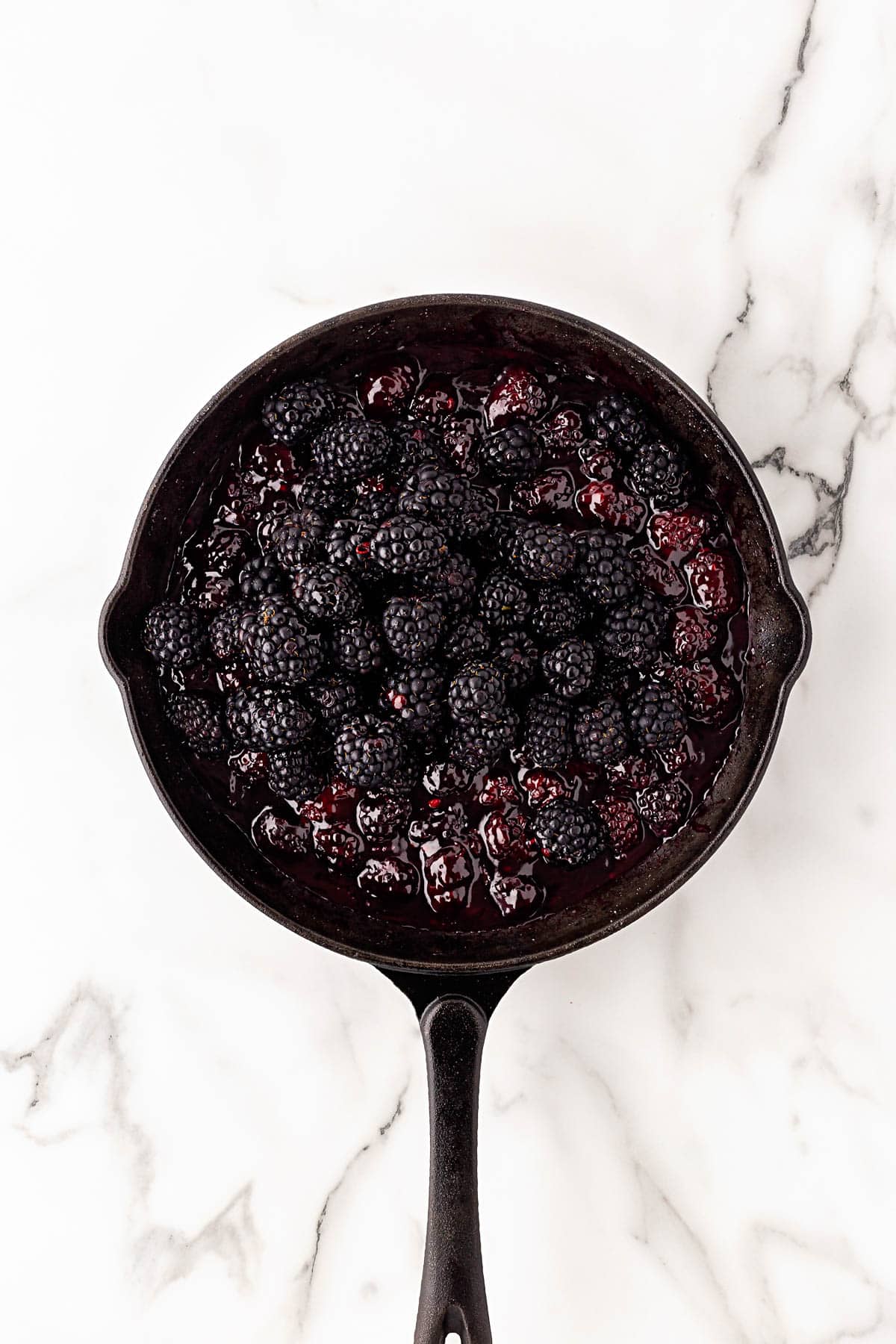 Thickened blackberry filling topped with fresh blackberries in skillet