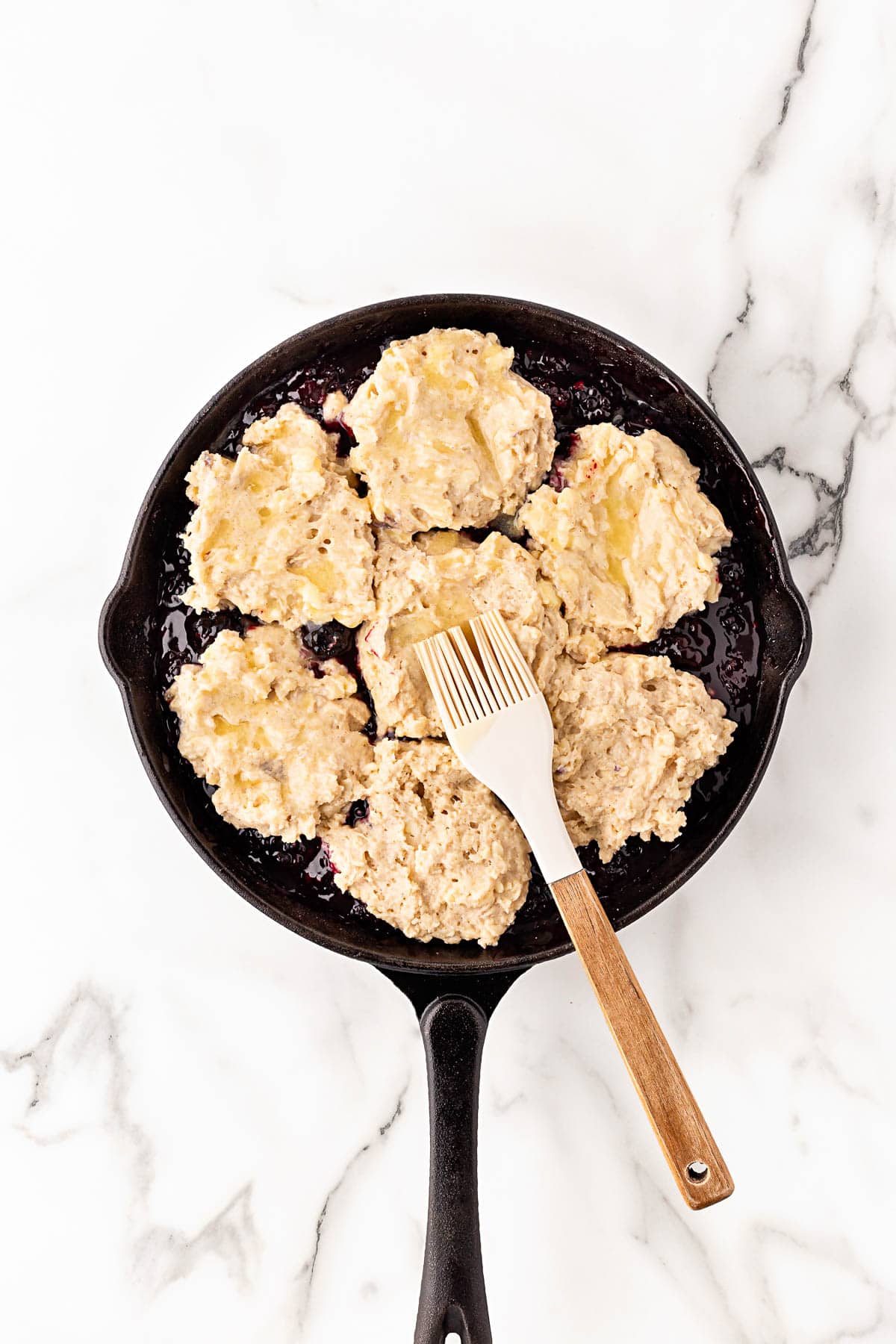 Blackberry cobbler biscuit topping dolloped over filling before baking