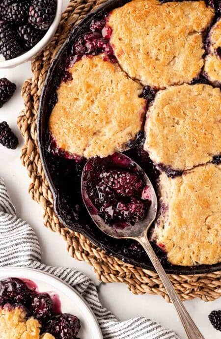 Overhead shot of spoon scooping warm blackberry cobbler from skillet