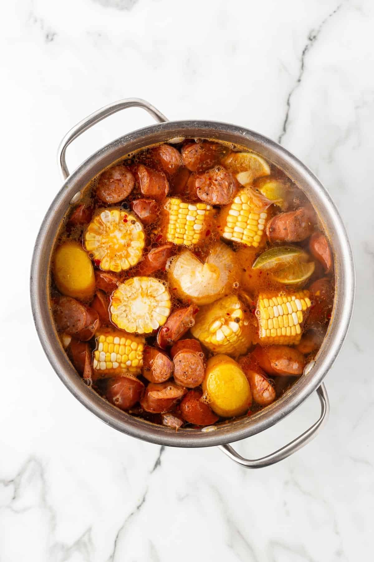 Sausage, corn, potatoes, and lemons simmering together in low country boil broth