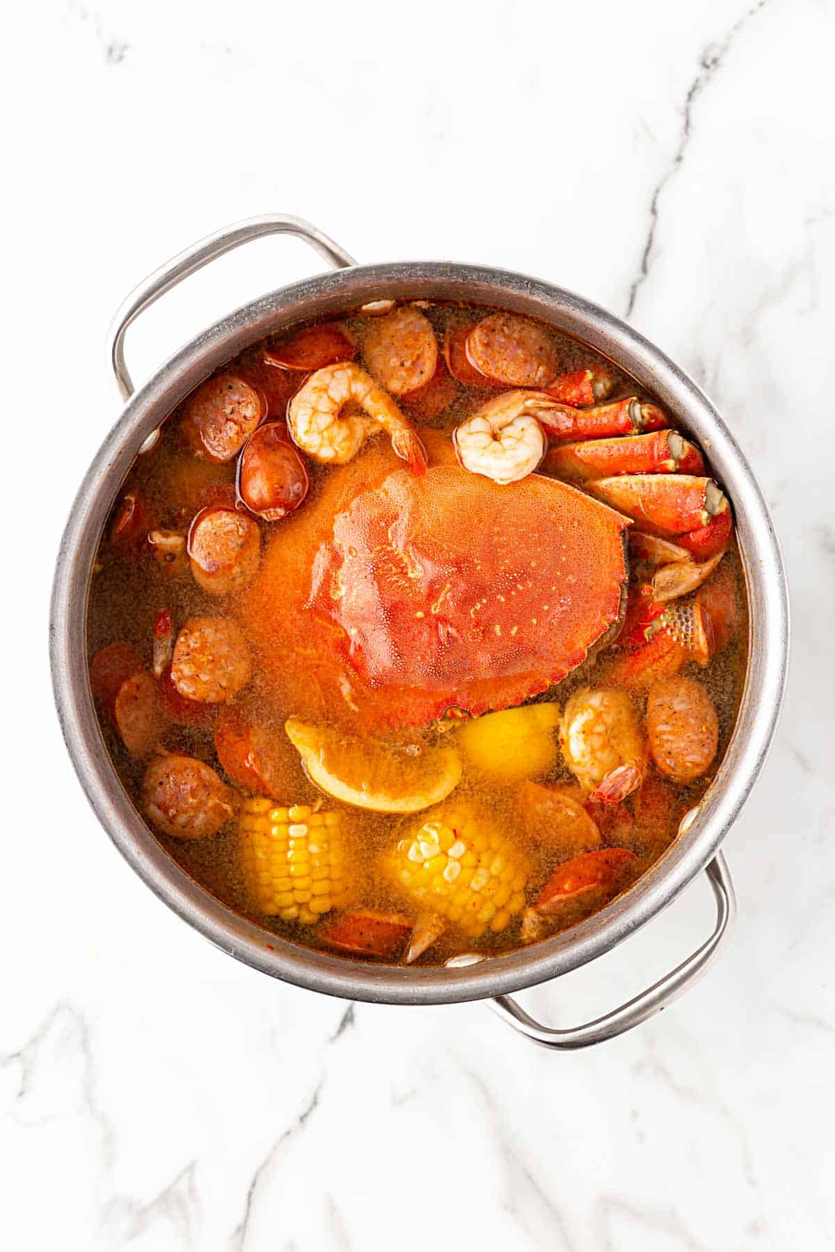 Whole crab and shrimp added to a pot of low country boil with sausage and corn