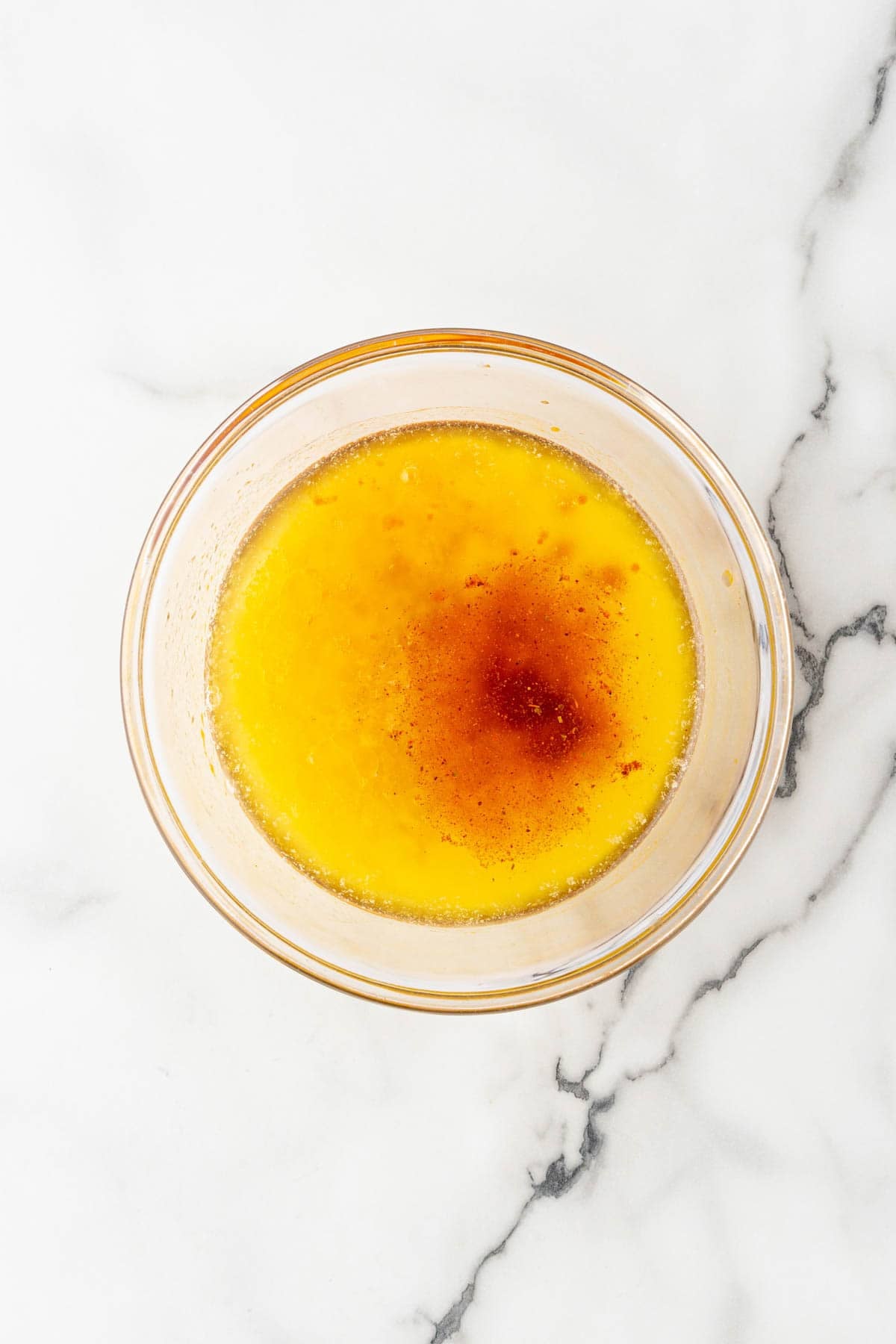 Melted butter seasoned with spices in a glass mixing bowl