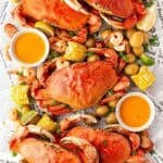Overhead shot of a finished low country boil spread with crabs, shrimp, corn, potatoes, sausage, and butter sauce