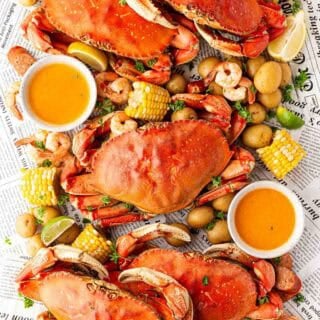 Overhead shot of a finished low country boil spread with crabs, shrimp, corn, potatoes, sausage, and butter sauce