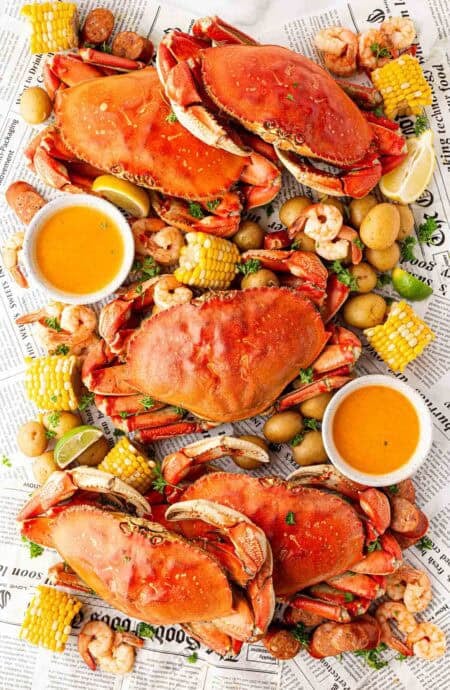 Overhead shot of a finished low country boil spread with crabs, shrimp, corn, potatoes, sausage, and butter sauce