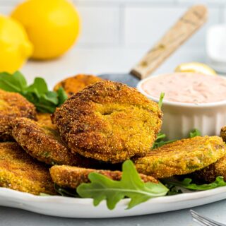 Salmon croquettes on a white platter with a spatula.