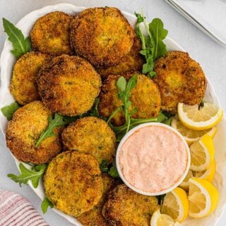 Overhead of salmon croquettes or salmon cakes on white platter with tartar sauce.