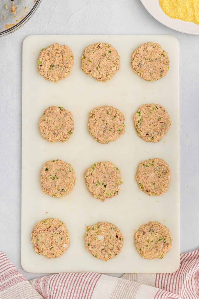 Salmon patties shaped on a cutting board.