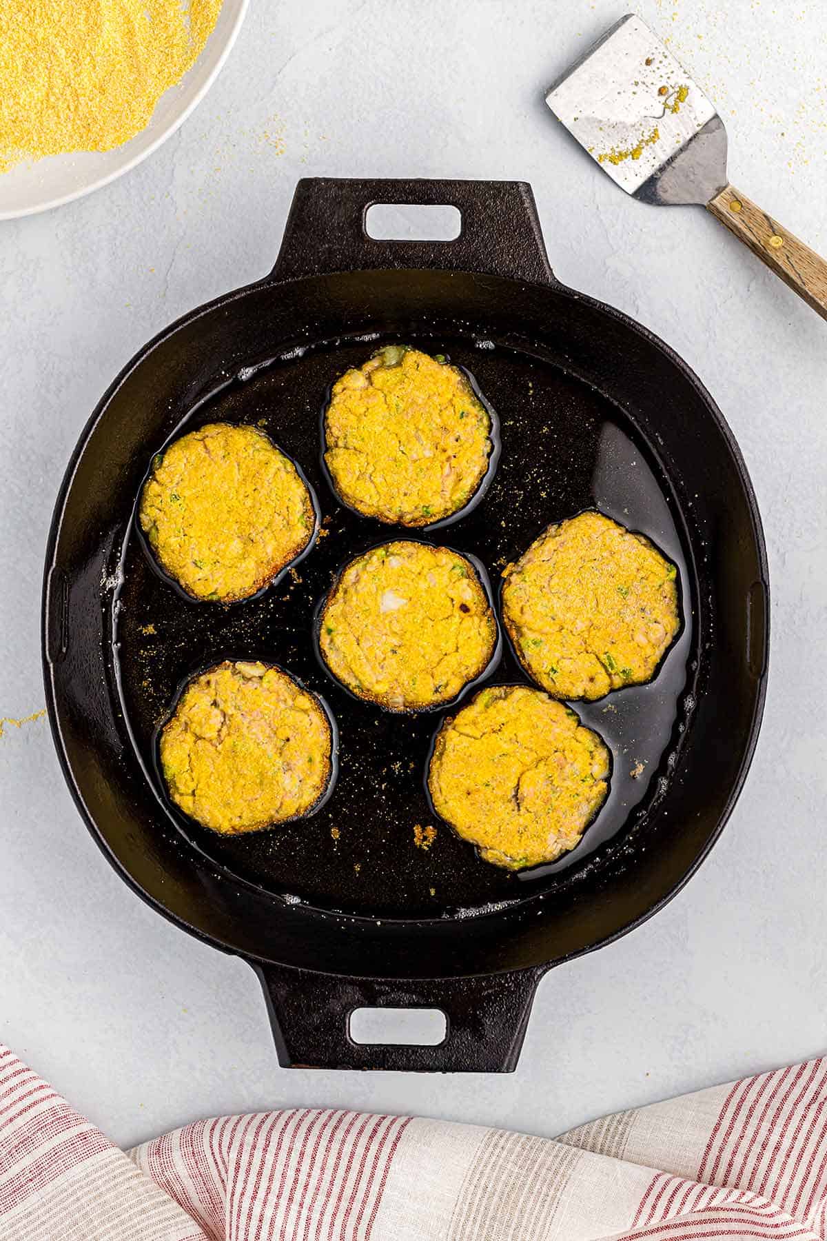 Southern Salmon croquettes are placed in a skillet to fry.