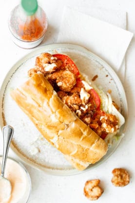 Overhead shot of po'boy with hot sauce and fried shrimp and remoulade sauce