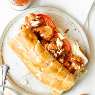 Overhead shot of po'boy with hot sauce and fried shrimp and remoulade sauce